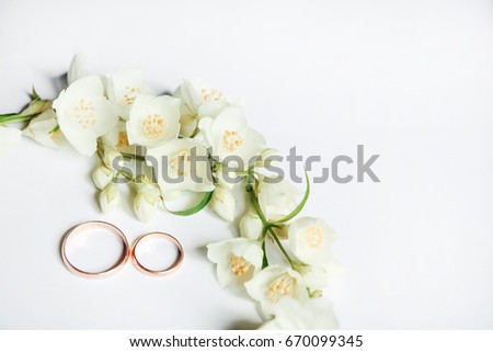 Gold wedding rings on a background of Jasmine flowers. Jasmine flowers in the form of a garland. Perfect for wedding invitations and greeting cards.