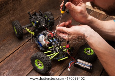 Rc radio control car crawler model toy electronics repair. Green toy suv in repairshop workplace, free space Royalty-Free Stock Photo #670099402