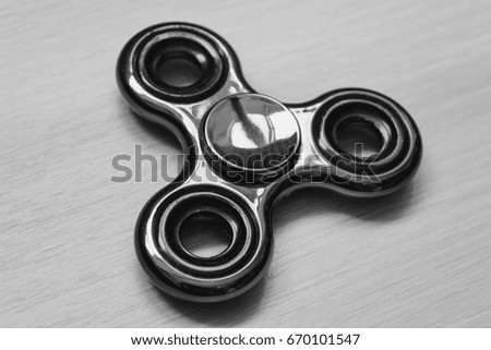 Metal shiny spinner in black and white style. Fidget spinner is a stress-resistant toy. Cool popular toy. Fidget finger spinner stress, toy for anxiety relief