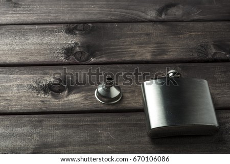 Metall hip flask with cup on wooden backdrop