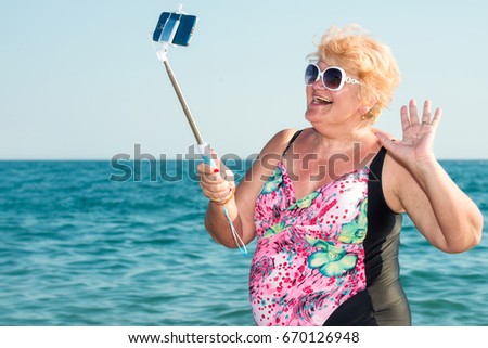  Woman taking a selfie on a mobile phone on the beach.Summer vacation.