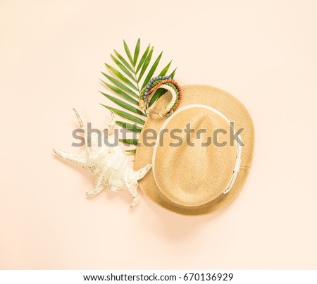 Summer fashion, summer outfit on cream background. Seashell, wood bracelet and straw hat. Flat lay, top view.