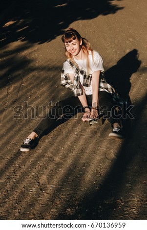Smiling hipster girl riding on skate board 