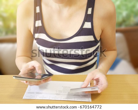 Woman using mobile phone paying bill online with credit card