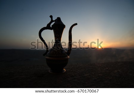 Decorative Arabian vase and jug pictured at sunset with fog