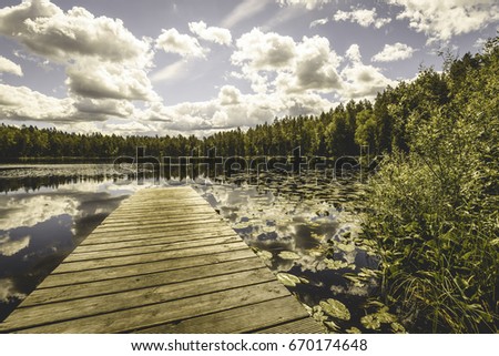 reflection of clouds in the lake with boardwalk and trees in background - vintage old effect