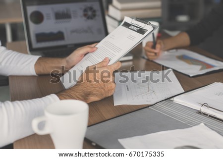 Closeup with man hand holding paper document on desk, Team collaborator worker discussing. Business Concept, vintage tone.