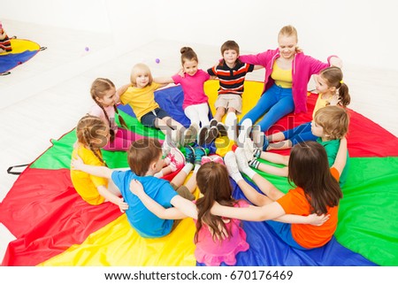 Happy children playing circle games with teacher