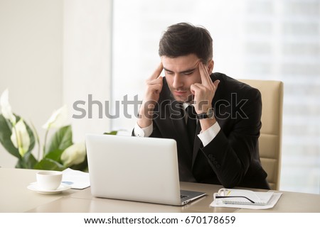 Serious frustrated businessman with closed eyes suffering from headache migraine at workplace, massaging temples, feeling tired exhausted, chronic work stress, tries to remember important information  Royalty-Free Stock Photo #670178659