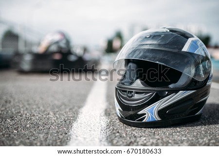 Racer helmet on asphalt, karting sport concept Royalty-Free Stock Photo #670180633