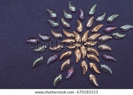 Beautiful glass leaves on a dark background fabric. Vintage background for needlework.Creative concept for embroidery and bead work
