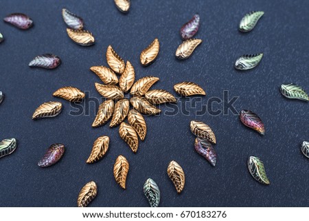 Beautiful glass leaves on a dark background fabric. Vintage background for needlework.Creative concept for embroidery and bead work
