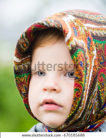 the child in the Russian headscarf outdoors in bright weather