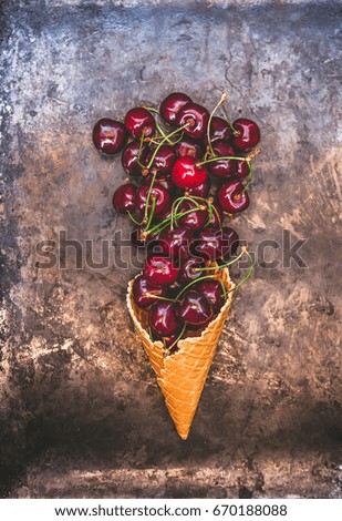 Fresh juicy cherry berries in a waffle cone on a dark old background, toned in retro style, top view.