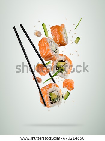 Flying sushi pieces served on plate, separated on colored background. Many kinds of popular sushi food with chopsticks. Very high resolution image