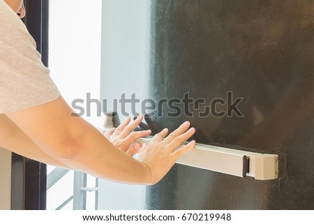 Hand is pushing/opening the emergency fire exit door Royalty-Free Stock Photo #670219948