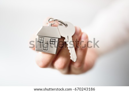 Holding house keys on house shaped keychain concept for buying a new home Royalty-Free Stock Photo #670243186