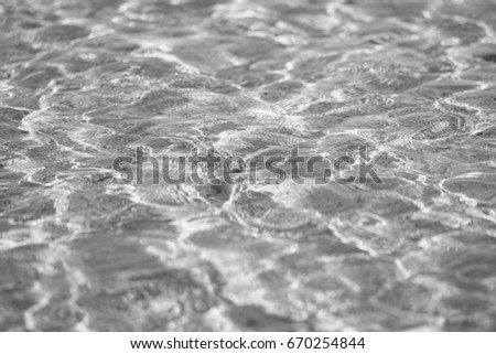 Water ripple in the sea with specks and light shines and reflections during low tide time, shallow water level and sandy bottom, abstract background or texture