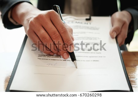 Real estate agent with hand putting signing contract,have a contract in place to protect it,signing of modest agreements form in office.Concept real estate,moving home or renting property