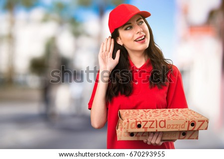 Pizza delivery woman listening something on unfocused background