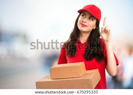 Young delivery woman pointing up on unfocused background