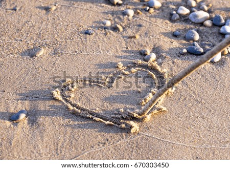 Heart drawn in sand with stick on clean beach shore, shiny wet pebbles love, vacation and holiday concepts
