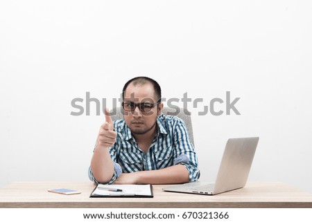 Portrait of young businessman with thumbs up sitting in workplace isolated on white background.