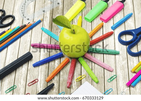 Close up of fresh apple with multicolored school supplies on the wooden table 