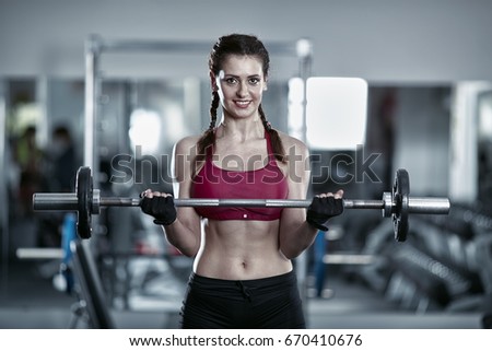 Young woman doing barbell curl, biceps workout