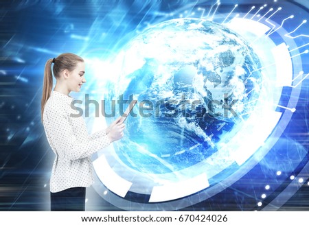 Blond businesswoman with a ponytail. She is wearing a white blouse and a black skirt and looking at a tablet computer she is holding. Globe and circuits. Elements of this image furnished by NASA