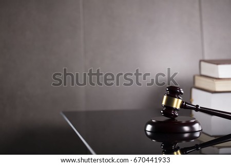 Law concept. Mallet of the judge, books, scales of justice. Gray stone background, reflections on the floor, place for typography. Courtroom theme.