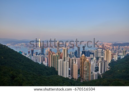 Hong Kong skyline. Hong Kong aerial cityscape with sunset sun. Amazing panorama of buildings and sky reflecting in harbour.
