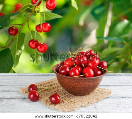 Sweet cherry in clay bowl  on the wooden table in garden 