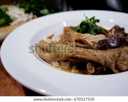 Good food good health, The picture of rice noodles in chicken feet and fish soup on white plate above wooden table.  selective focus