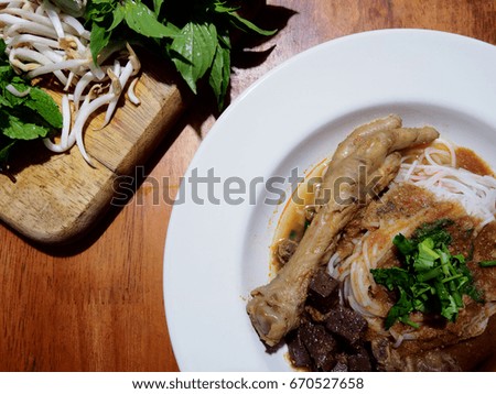 Good food good health, The picture of rice noodles in chicken feet and fish soup on white plate above wooden table.