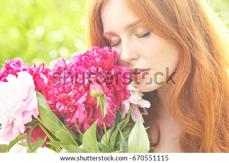 summer closeup portrait of a young redhead woman with flowers. Tender girl and pink peonies