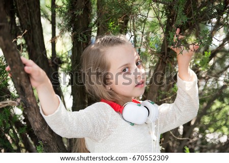 Cute little girl enjoying music using headphones at summer day