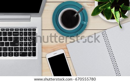 Wooden desktop with objects needed for work. Modern laptop, smartphone, cup of coffee and notepad with blank sheets laying at wooden table. Home workspace. Education or business concept. Devices