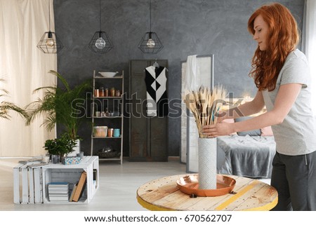 Young woman with red hair decorating contemporary fancy industrial apartment Royalty-Free Stock Photo #670562707