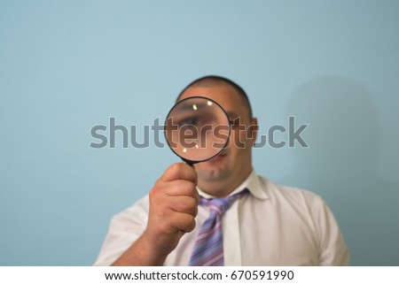Businessman in a suit looks through a magnifying glass