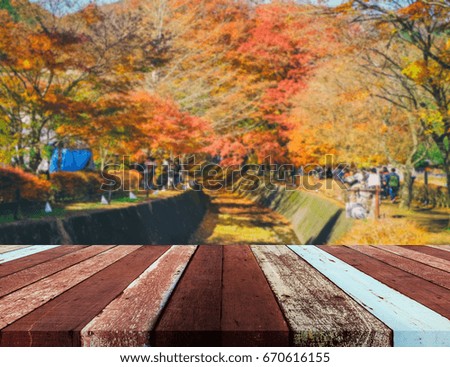 image of wood table and  blur red maple tree in background.