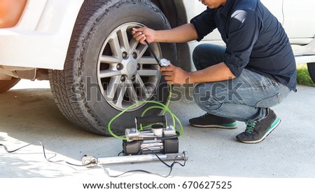man checking air pressure and filling air in the tires of his car,Man checking air pressure and filling air in the tires of car. Concept picture