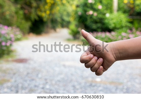 Asian boy show thumb up with blurred way background (Concept for hitch hiking, good work, like)