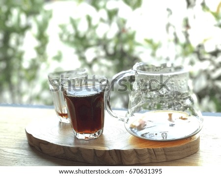 Hot black coffee in clear glass is placed on a wooden table. 