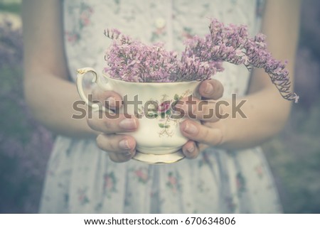 Girl hands holding a fine bone china teacup with a bouquet of lilac flowers - Giving Spring flowers - Shabby chic blossom - Vintage edition