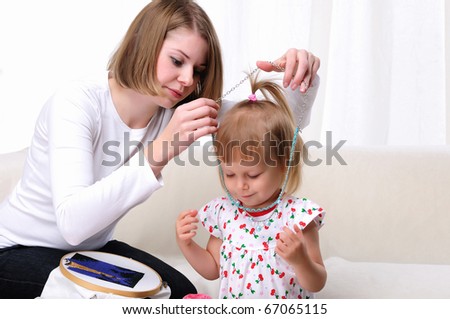Young mother and her baby daughter spending time together. Dress up in costume jewelry.