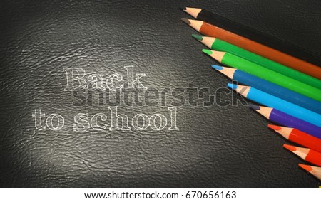 Photo of crayons on black backdrop with inscription Back to school