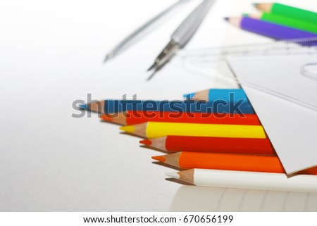 Photo of crayons with compass on exercise book and a paper