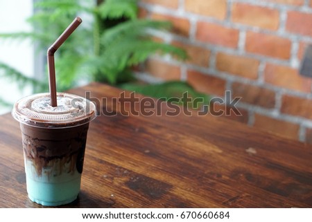 A plastic glass of refreshing iced chocolate mixed with pastel peppermint on wooden table and copy space.