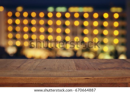 wooden board table in front of night bokeh hotel. Ready for product display montages